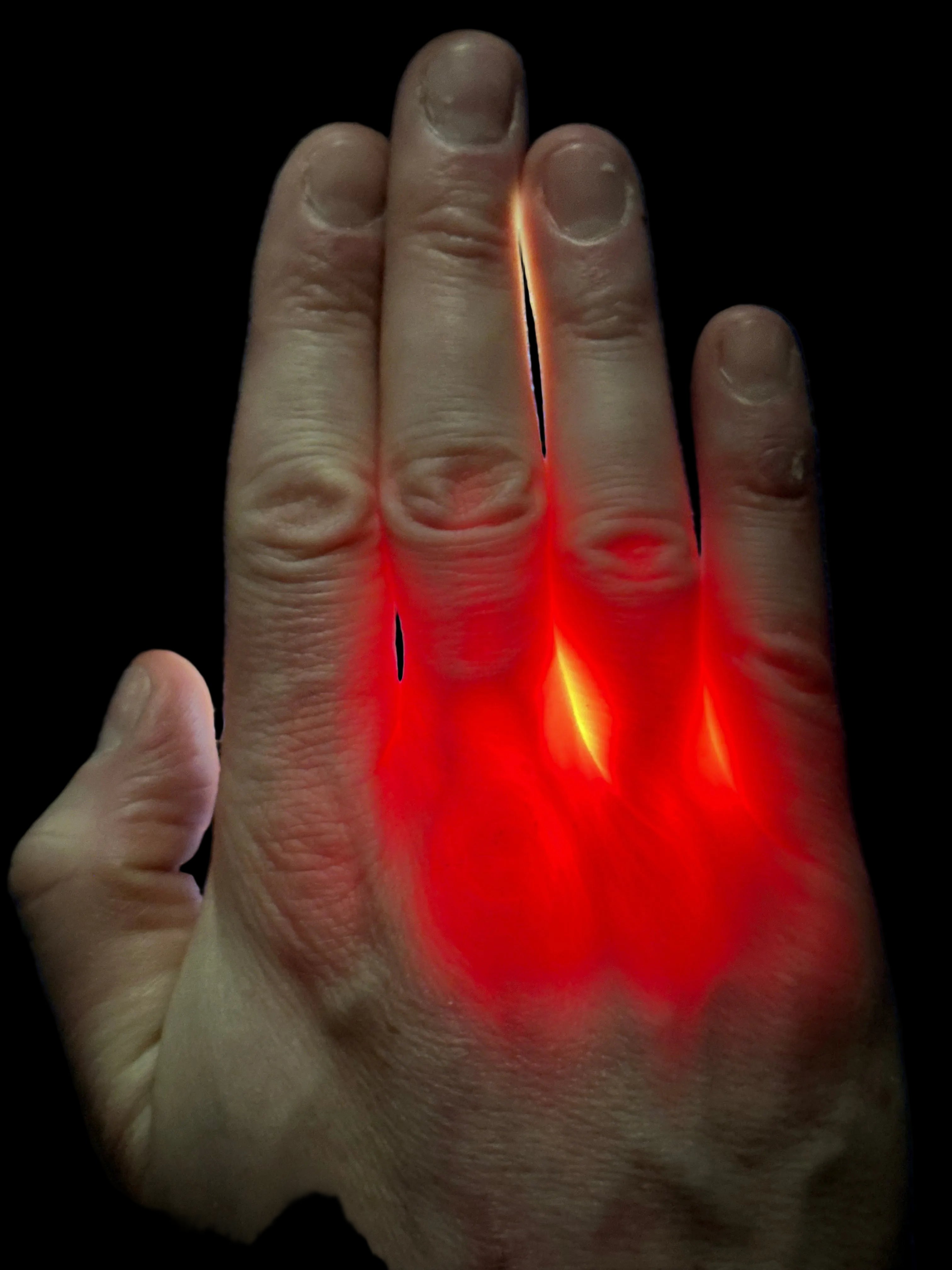 Hand with red light glowing on a dark background